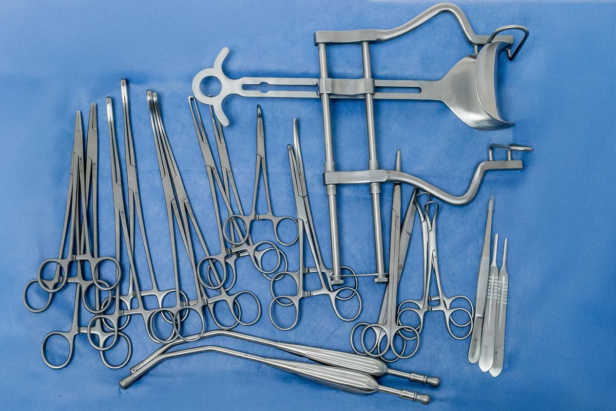 Pinzas, tijeras y separadores quirúrgicos sobre tela azul